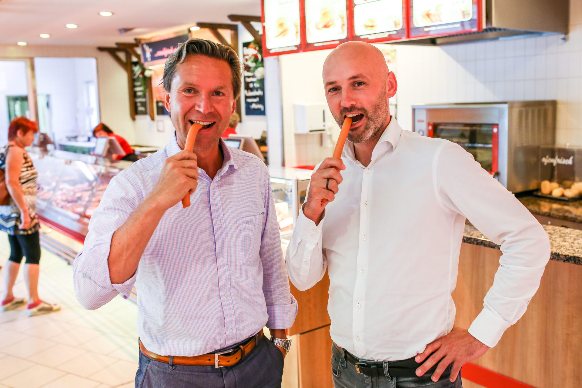 Michael Korch und Felix Alber stehen im Werksverkauf der Radeberger Produktionsstätte und beißen ins Würstchen